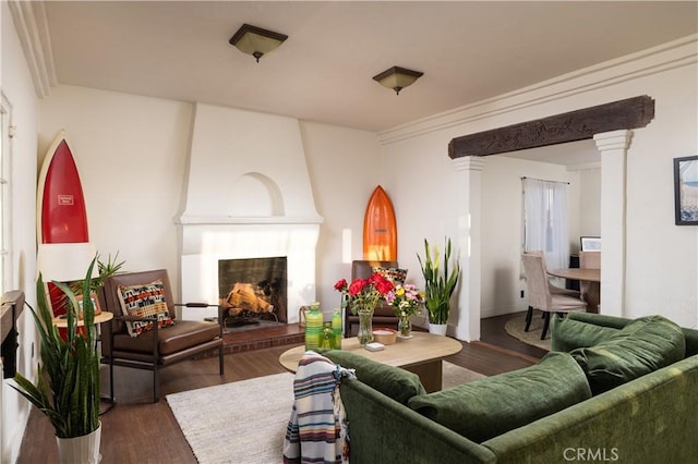 living room with dark hardwood / wood-style floors, ornamental molding, a fireplace, and ornate columns