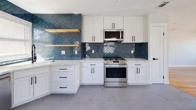 kitchen with white cabinetry, stainless steel appliances, sink, and backsplash