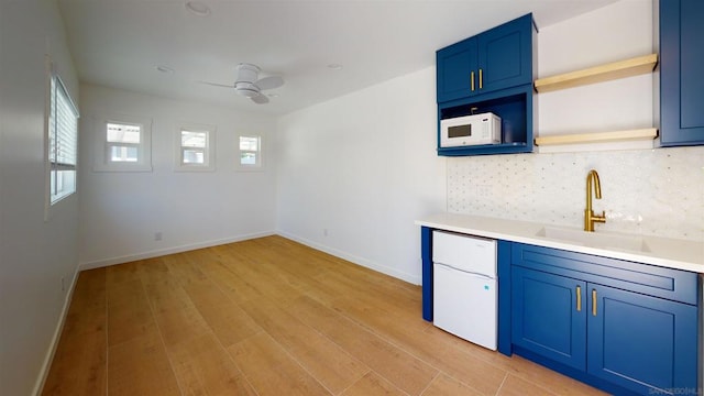 kitchen featuring blue cabinets, sink, ceiling fan, light hardwood / wood-style floors, and backsplash