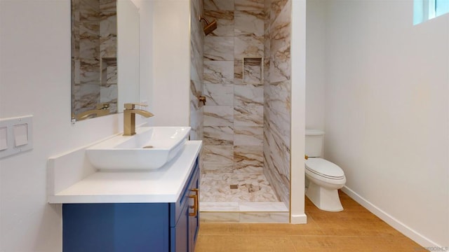 bathroom with vanity, tiled shower, hardwood / wood-style floors, and toilet