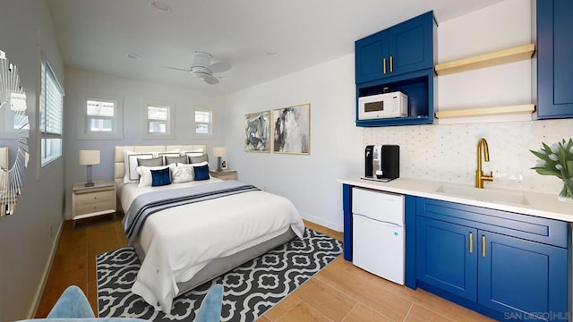 bedroom featuring ceiling fan, fridge, sink, and light wood-type flooring