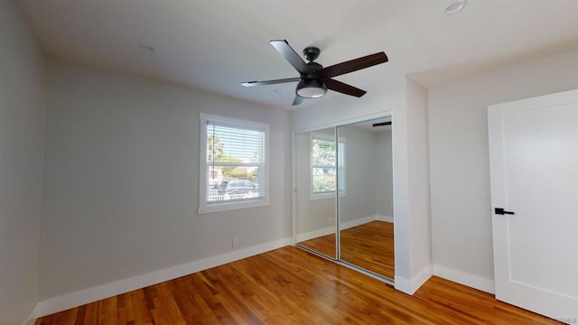 unfurnished bedroom with ceiling fan, wood-type flooring, and a closet