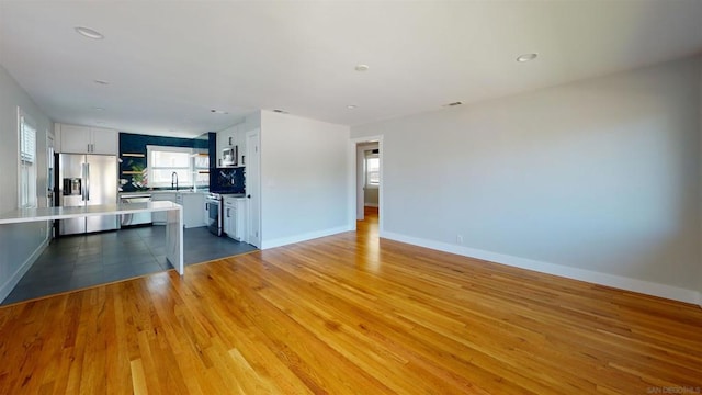 unfurnished living room featuring sink and light hardwood / wood-style floors