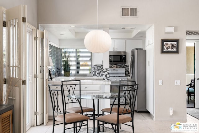 dining room featuring light tile patterned floors and a tray ceiling