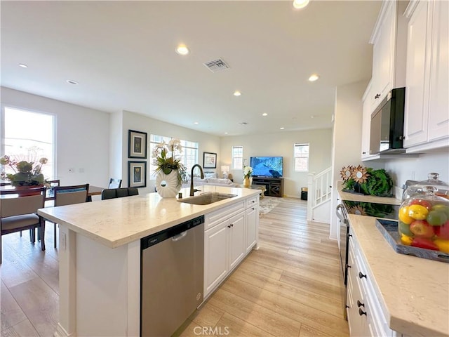 kitchen with an island with sink, dishwasher, sink, and white cabinets