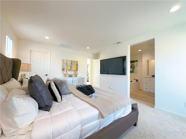 bedroom featuring light carpet and ensuite bath