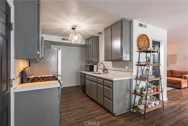 kitchen featuring pendant lighting, sink, dishwasher, gray cabinetry, and dark hardwood / wood-style flooring