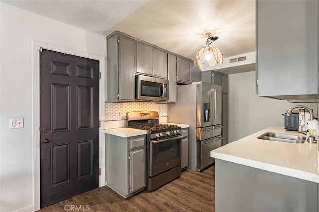 kitchen with pendant lighting, sink, dark wood-type flooring, gray cabinetry, and stainless steel appliances