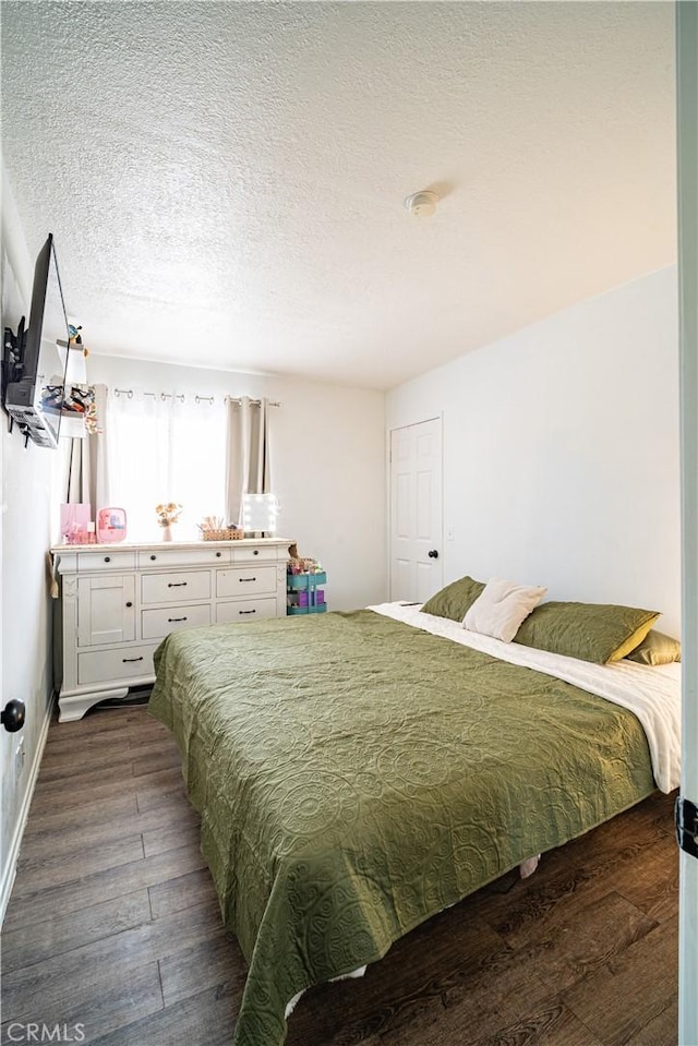 bedroom featuring dark hardwood / wood-style flooring and a textured ceiling