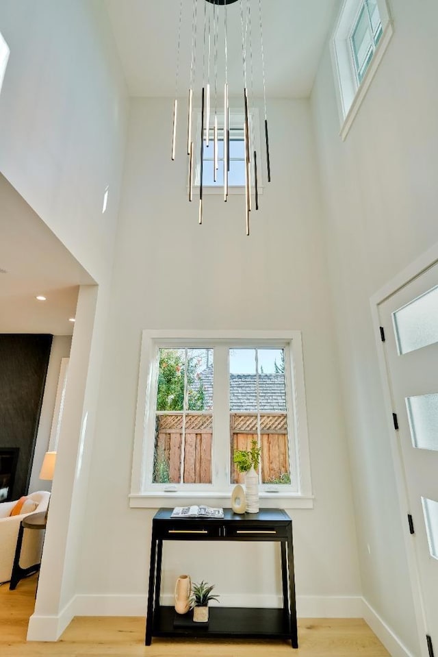 foyer entrance with a towering ceiling and light wood-type flooring