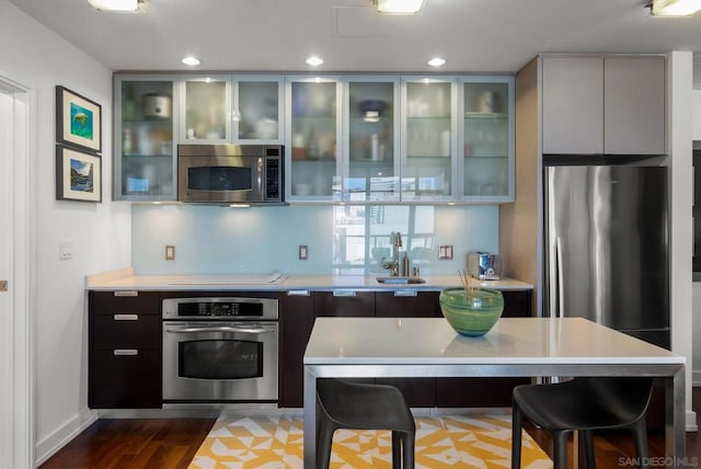 kitchen with sink, hardwood / wood-style floors, stainless steel appliances, and a breakfast bar