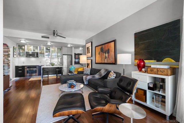 living room with ceiling fan and dark hardwood / wood-style flooring