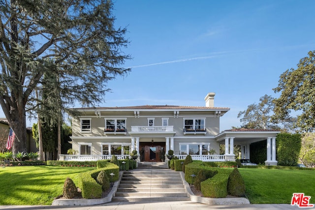 view of front of house with a balcony and a front yard