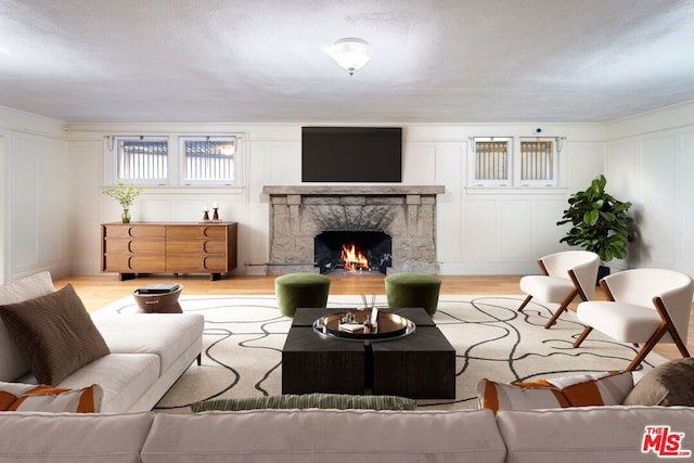 living room featuring a textured ceiling, a fireplace, and light wood-type flooring