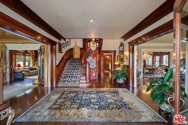 foyer with an inviting chandelier, crown molding, and dark hardwood / wood-style floors