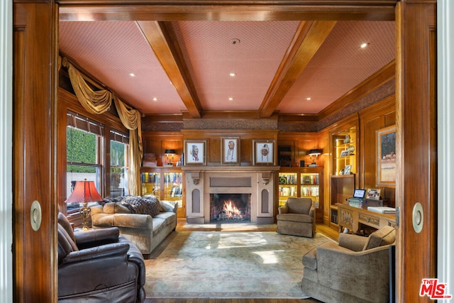 living room featuring built in features, beam ceiling, and wood walls