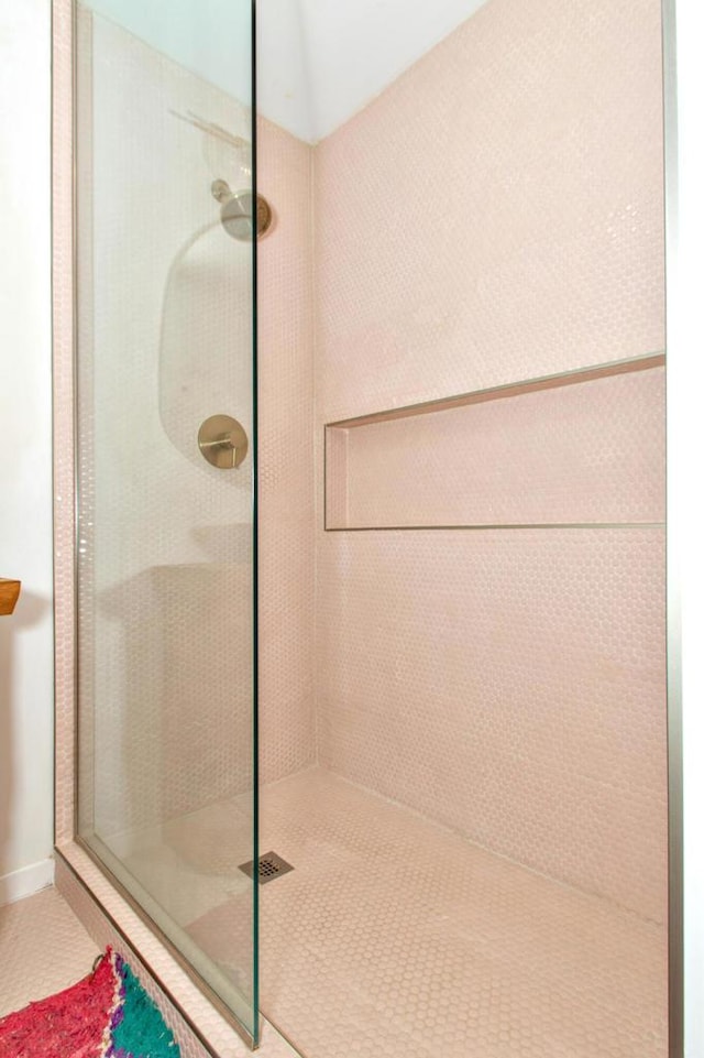 bathroom with tiled shower and tile patterned floors