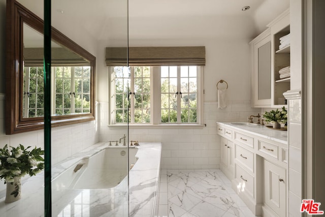 bathroom with vanity, tile walls, and a bathtub