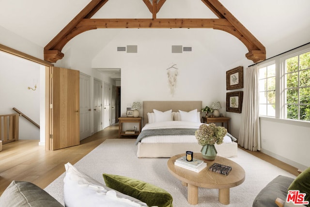 bedroom featuring beamed ceiling, high vaulted ceiling, and light wood-type flooring