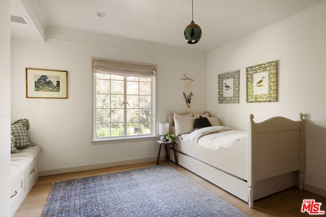 bedroom with crown molding and light wood-type flooring