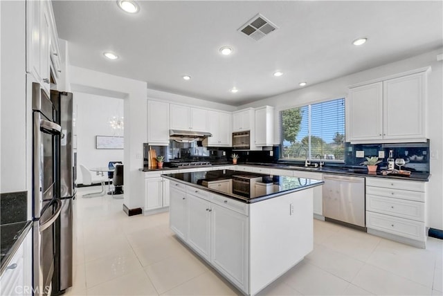 kitchen featuring backsplash, stainless steel appliances, a kitchen island, and white cabinets