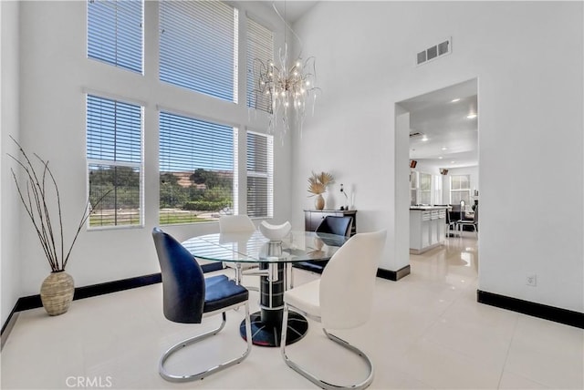 dining area featuring a towering ceiling, a chandelier, and light tile patterned flooring