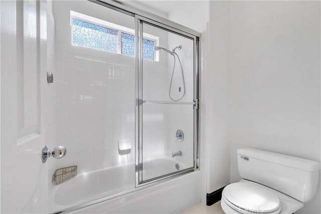 bathroom with combined bath / shower with glass door and toilet