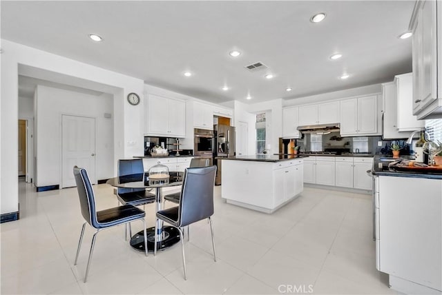 kitchen featuring sink, stainless steel appliances, white cabinets, a kitchen island, and decorative backsplash