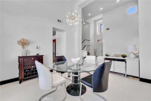 dining area with light tile patterned floors, a towering ceiling, and a chandelier