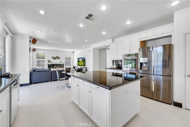 kitchen featuring light tile patterned floors, stainless steel appliances, a center island, and white cabinets