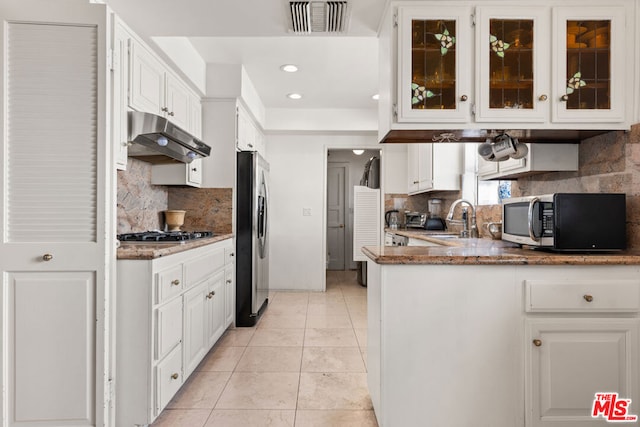 kitchen featuring light tile patterned flooring, sink, white cabinetry, stone countertops, and appliances with stainless steel finishes