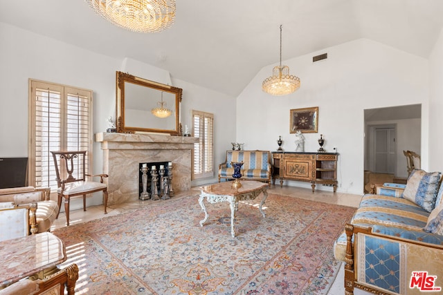 tiled living room featuring a premium fireplace, a chandelier, and high vaulted ceiling