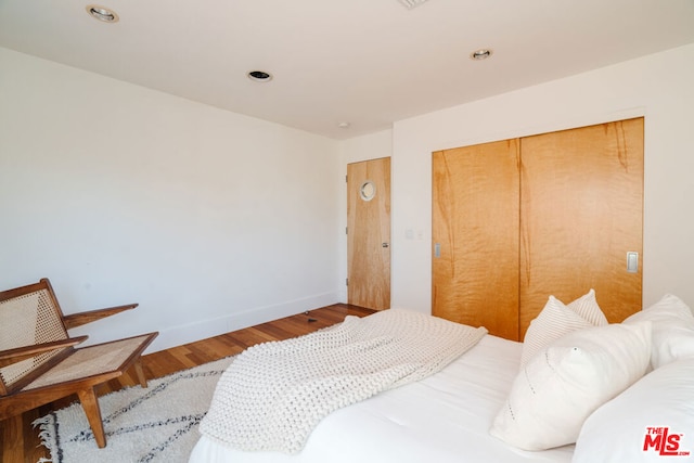 bedroom with wood-type flooring and a closet