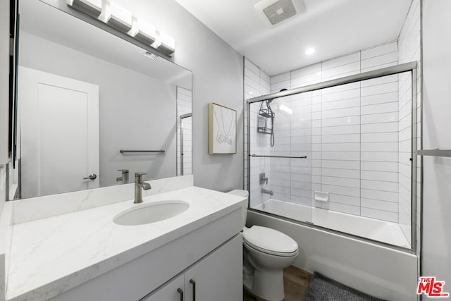 full bathroom featuring bath / shower combo with glass door, vanity, and toilet