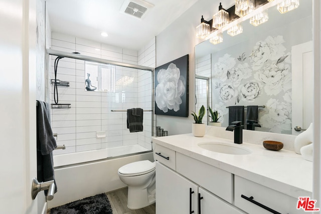 full bathroom featuring hardwood / wood-style flooring, vanity, toilet, and combined bath / shower with glass door