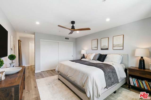 bedroom featuring light hardwood / wood-style floors, a closet, and ceiling fan