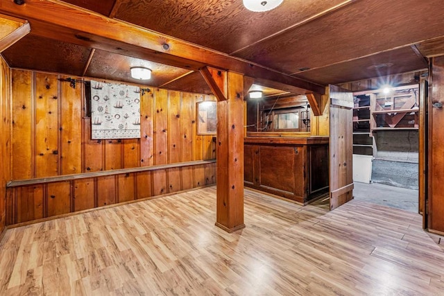 basement featuring light hardwood / wood-style floors and wood walls