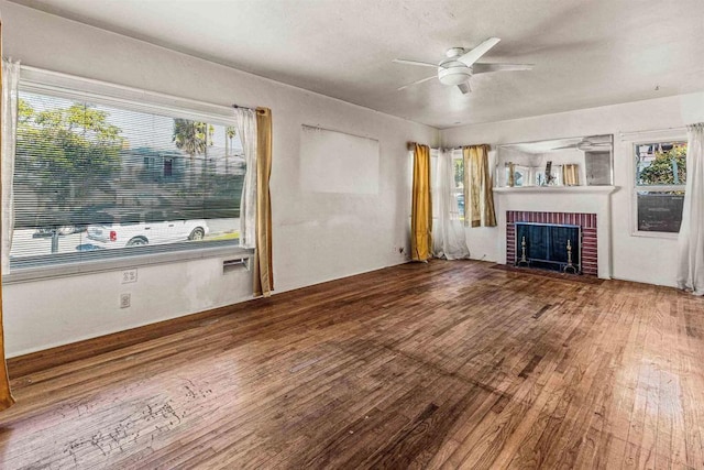 unfurnished living room featuring ceiling fan, wood-type flooring, and a brick fireplace