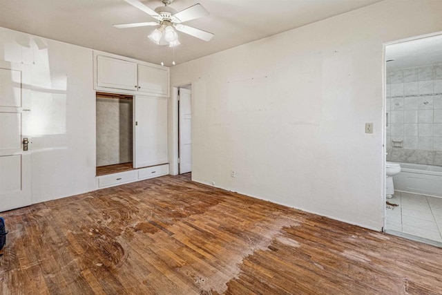 unfurnished bedroom with ceiling fan, connected bathroom, and hardwood / wood-style floors