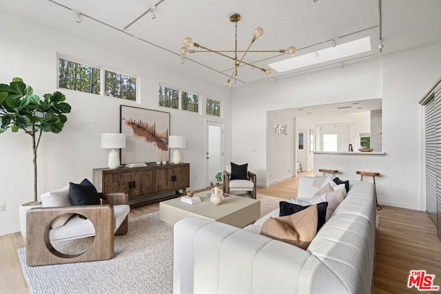 living room with a notable chandelier, light hardwood / wood-style flooring, and track lighting