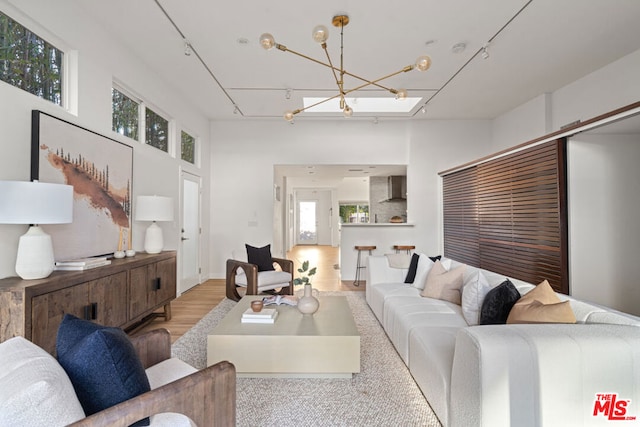 living room with light hardwood / wood-style flooring, rail lighting, a chandelier, and a high ceiling