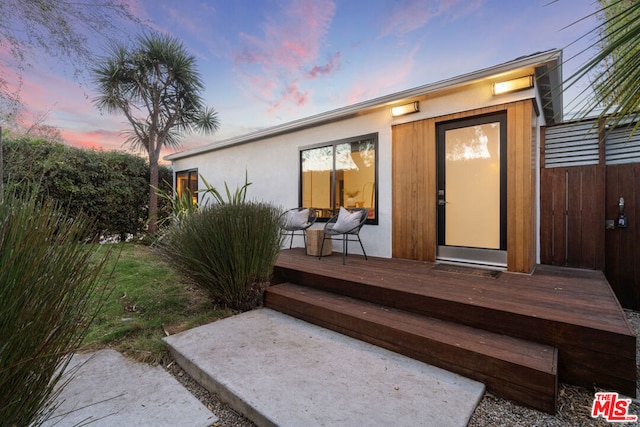 exterior entry at dusk with a wooden deck