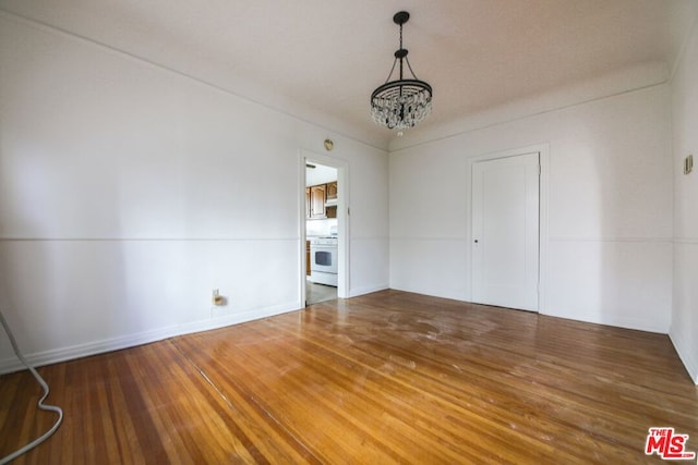 empty room featuring dark hardwood / wood-style floors and an inviting chandelier