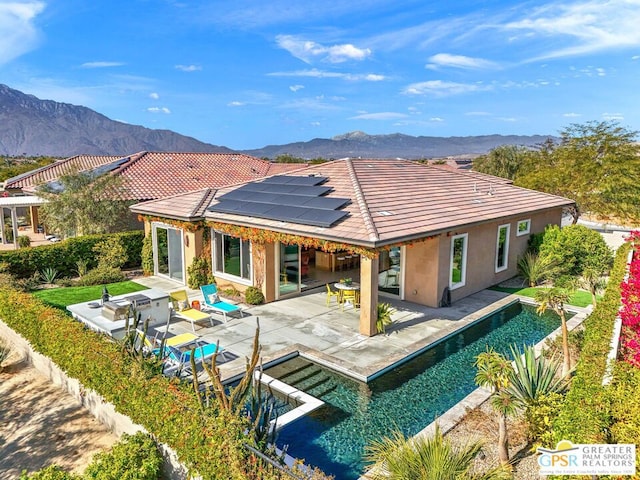 back of house with a mountain view, a patio area, and solar panels