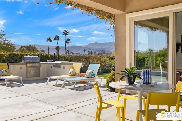 view of patio / terrace with an outdoor kitchen, a mountain view, and area for grilling