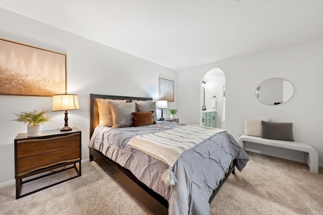 bedroom featuring connected bathroom and light carpet