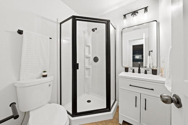 bathroom featuring tile patterned flooring, toilet, vanity, and walk in shower