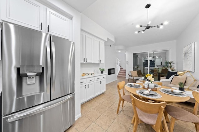 kitchen with stainless steel fridge with ice dispenser, a notable chandelier, white cabinets, and light tile patterned flooring