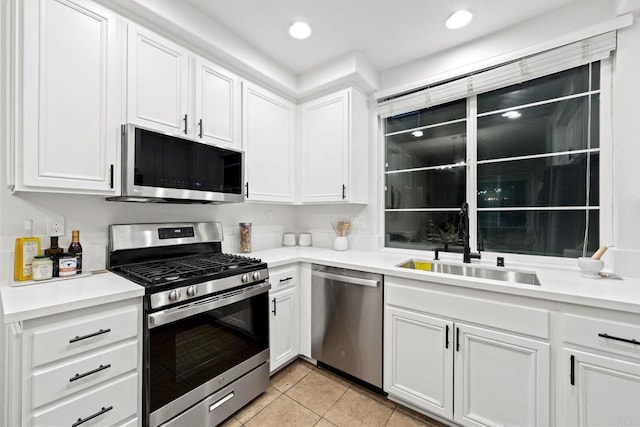 kitchen featuring appliances with stainless steel finishes, sink, light tile patterned floors, and white cabinets