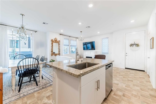 kitchen with sink, decorative light fixtures, a kitchen island with sink, and white cabinets